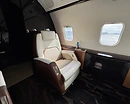 AeroForm aircraft leather cleaning and conditioning — cream leather passenger seat with high-gloss wood veneer console in a private jet cabin in Monterey, CA