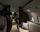 AeroForm interior aircraft detailing — private jet cabin aisle with beige leather seating and espresso high-gloss wood bulkheads, cleaned and sanitized at Monterey Regional Airport (MRY)