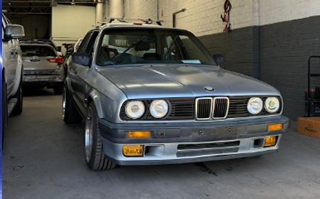 Silver BMW E30 classic sedan inside the workshop