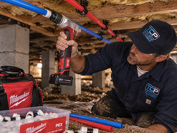Professional plumber installing new PEX piping in a residential crawlspace