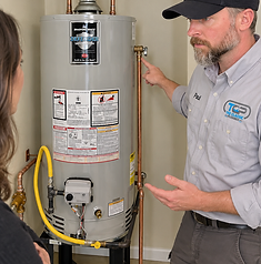 Professional plumber inspecting a residential gas water heater in a Knoxville garage