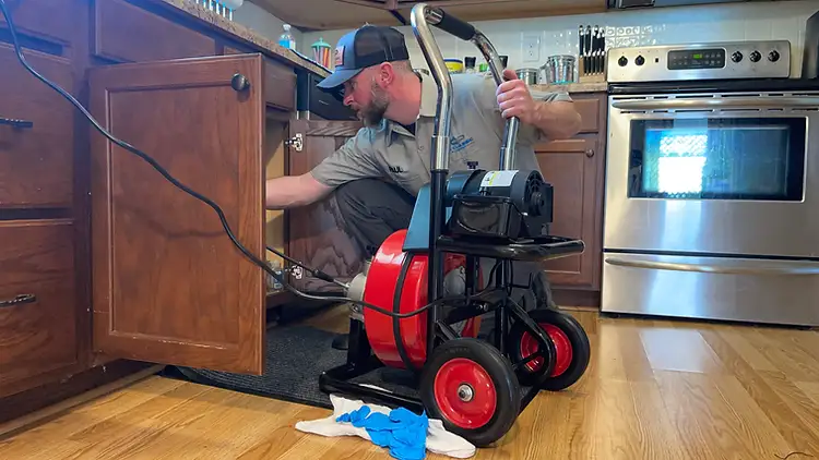 Feeding a professional drain auger cable into a kitchen sink drain