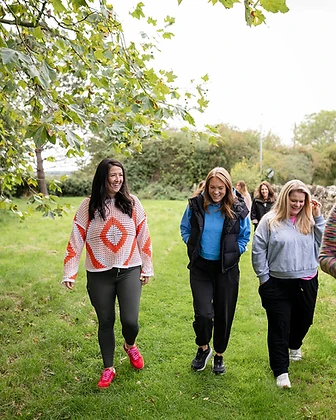 Four members walking together outdoors on a green path