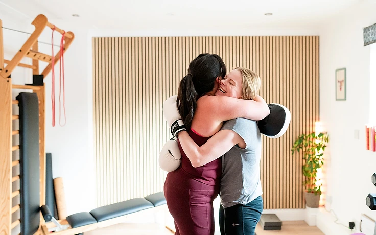 Two women sharing a joyful hug after a small group training session