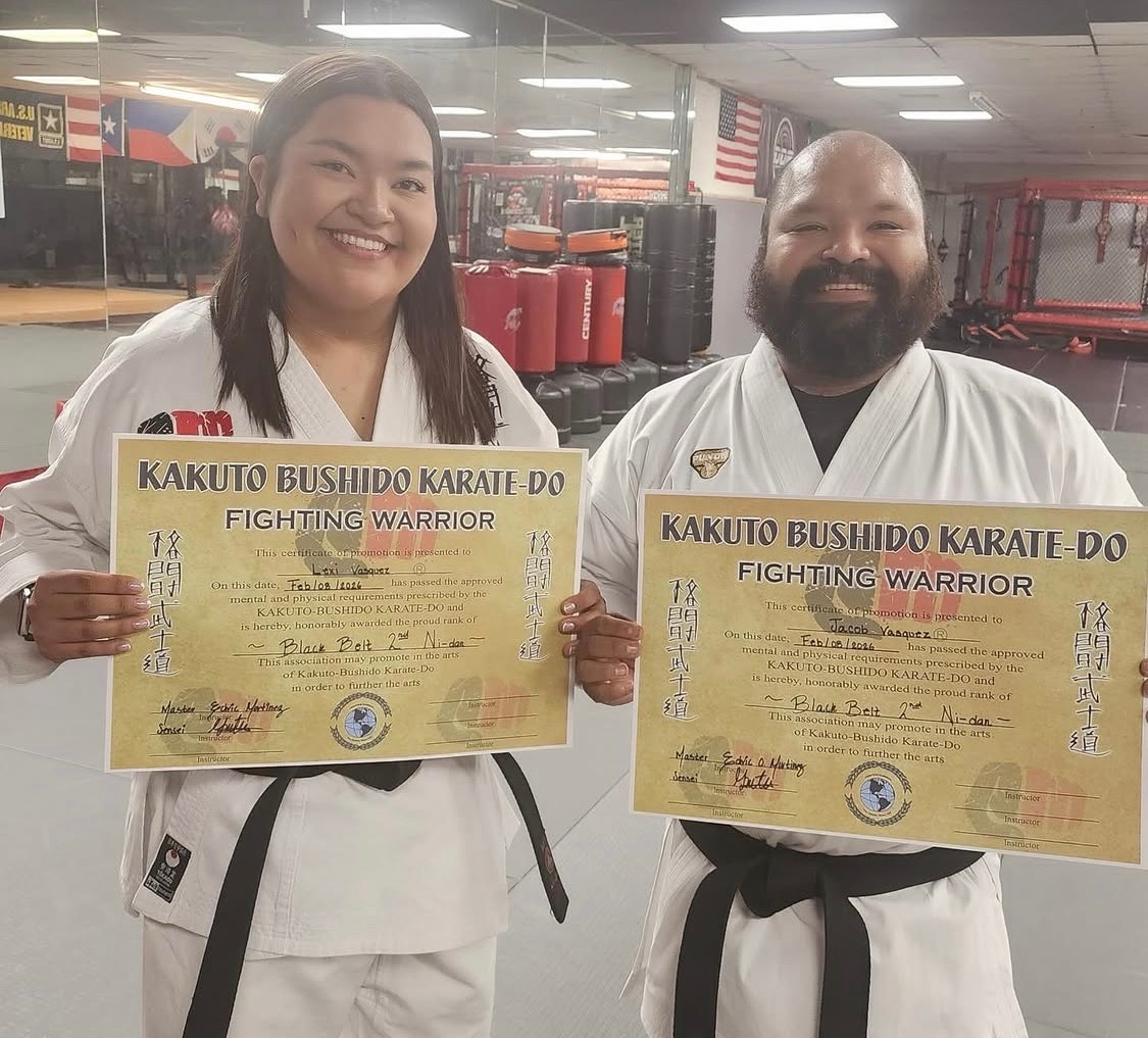 Sensei Jake and Lexi Vasquez holding their Kakuto Bushido Karate-Do certificates in the dojo