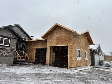 Attached two-bay garage with exterior sheathing in place during snowfall