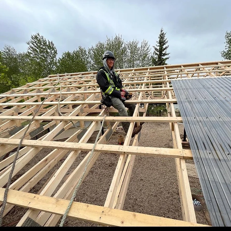 Carpenter working on roof framing at a construction site