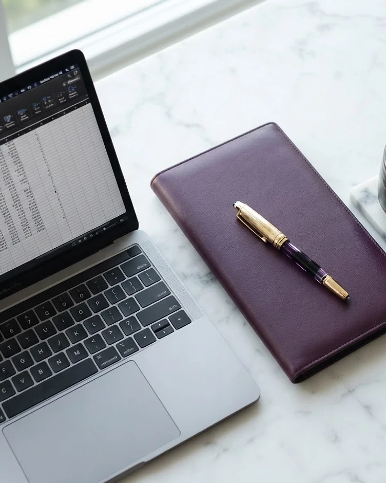 Tax professional's desk with calculator, financial documents, and laptop used in Tax School Dropout's hybrid tax preparer training