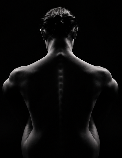 Black-and-white photograph of a person's bare back, head bowed, lit from behind