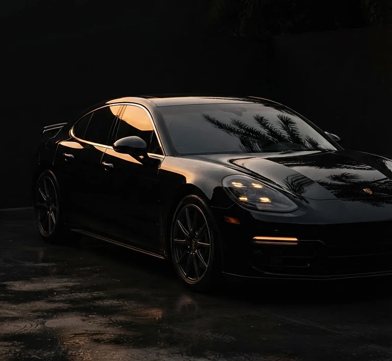Pristine black luxury vehicle emerging from shadow