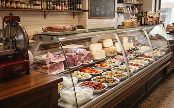 Traditional Italian deli counter with a glass display case of cured meats, cheeses and olives