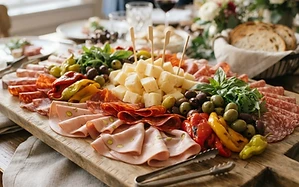 Cold cut platter with folded mortadella, soppressata and salami around provolone, peppers and olives