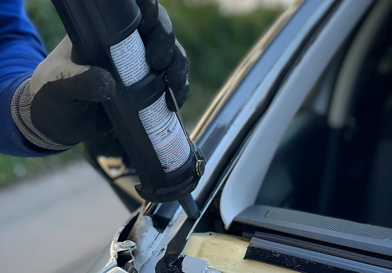 A Phantom AutoGlass technician sealing a windshield frame with professional-grade adhesive