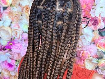 Back view of long jumbo box braids cascading against a neutral clay background