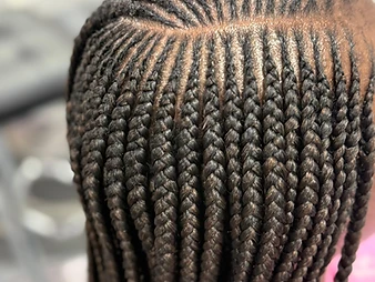 Close-up of hands weaving feed-in cornrows with directional side lighting