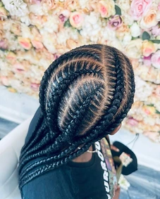 Cornrows sweeping back from the scalp against a floral wall