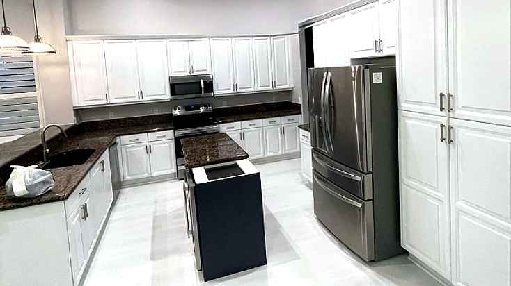 Kitchen after renovation with white cabinets and navy island