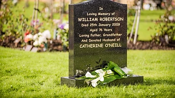 Flowers placed at a memorial headstone in a cemetery garden