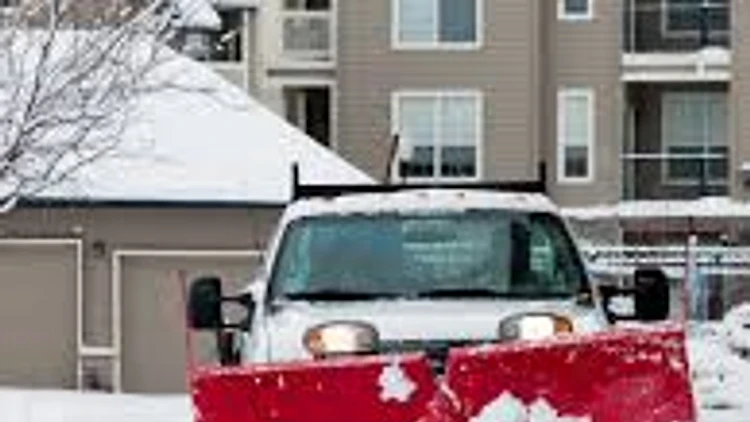 Snowplow truck clearing a residential driveway after snowfall