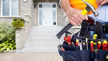 Professional maintenance worker with tool belt and hard hat at a residential home