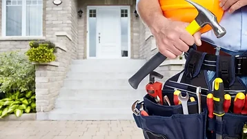 Professional maintenance worker with tool belt and hard hat at a residential home
