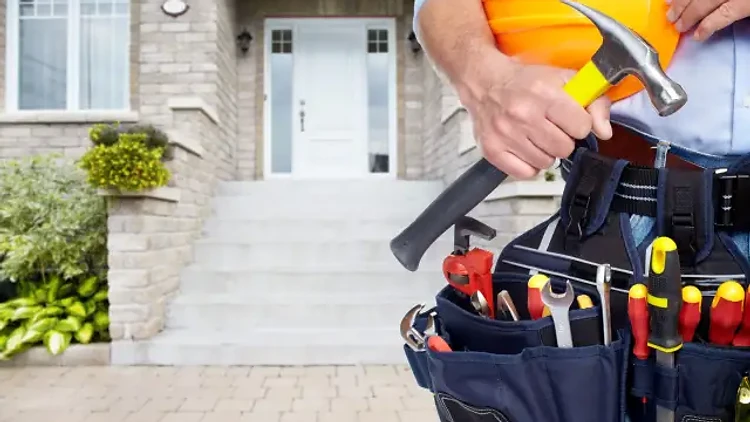 Professional maintenance worker with tool belt and hard hat at a residential home