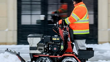 Operator clearing snow with a walk-behind snow blower