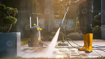 Pressure washing a paved patio at golden hour