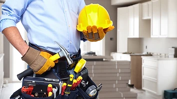 Handyman with a tool belt and hard hat inside a residential kitchen
