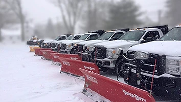 Fleet of snowplow trucks lined up on a snowy day