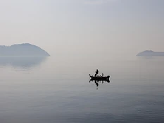 琵琶湖の静かな水面に1隻のボートが浮かぶ。モノトーンのような穏やかな情景。