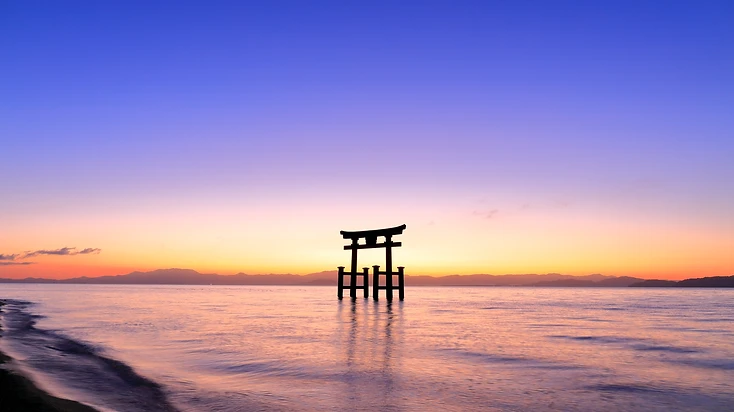 琵琶湖に立つ白鬚神社の鳥居。夕陽に染まる水面と空。