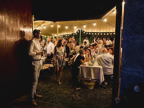 Soirée intime de mariage sous une tente stretch éclairée par des guirlandes la nuit