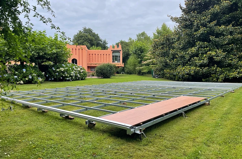 Structure de plancher sur appuis réglables installée sur une pelouse devant un bâtiment patrimonial