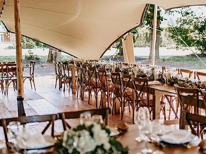 Dîner dressé sous une tente stretch, guirlandes lumineuses et tables alignées