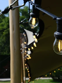 Guirlandes guinguette à lumière chaude suspendues sous une tente stretch