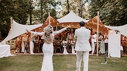 Réception de mariage dressée sous une tente stretch entre les arbres