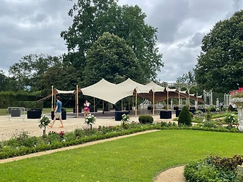 Tente stretch beige vide dressée sur un plancher dans un jardin entouré de haies