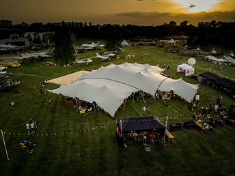 Tente stretch dressée sur un terrain d'exposition d'avions anciens au coucher du soleil