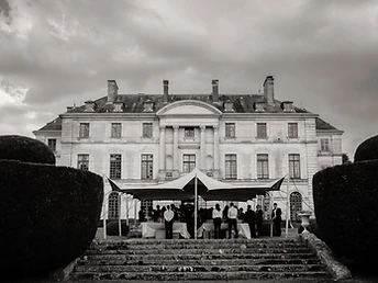 Tente stretch dressée devant un château en pierre avec buffet et service