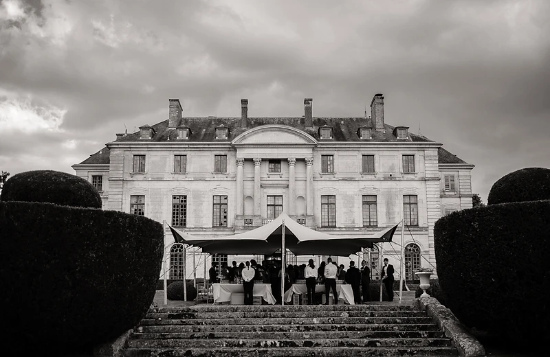 Tente stretch dressée devant un château en pierre, en lien direct avec le paysage