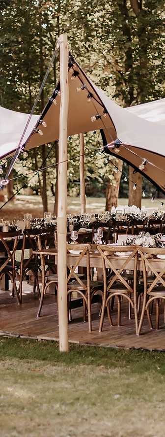 Tente stretch dressée sur plancher bois avec tables dressées et guirlandes