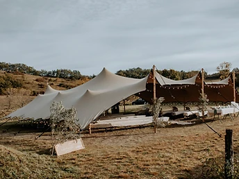 Tente stretch beige éclairée par des guirlandes pour une cérémonie laïque en pleine nature