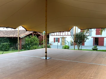 Plancher bois verni posé sous une tente stretch, vue sous la toile vers le paysage