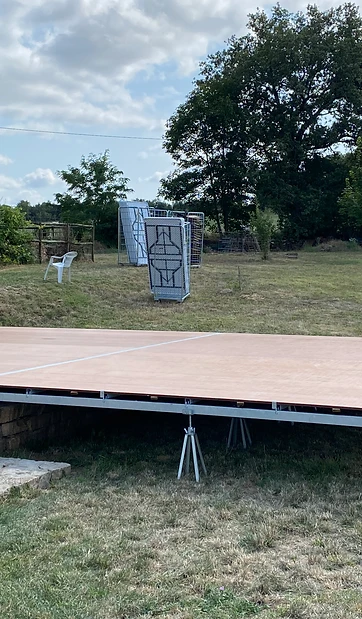 Plancher sur appuis réglables installé devant un mur en pierre, adaptation au terrain et aux abords du lieu