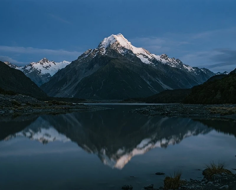 Southern Alps reflected in a still glacial lake at blue hour