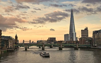 The blue Victorian facade of a historic London Bridge building, with the Shard rising behind it against a clear sky.