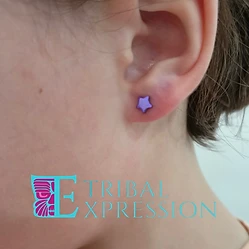 A close-up of a child’s earlobe with a purple star-shaped stud earring.