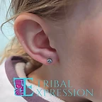 A close-up of a child’s earlobe with a small light-blue gemstone stud earring.