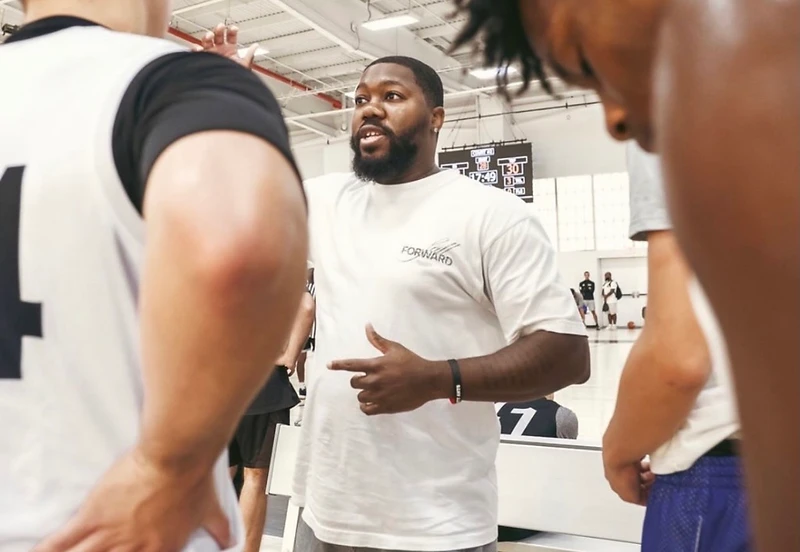 A coach instructing young athletes in a huddle on a basketball court